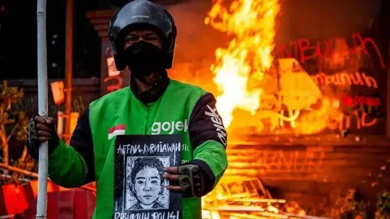 ◆抗议活动中，一名身穿绿色夹克的摩托车骑手手持阿凡的肖像。