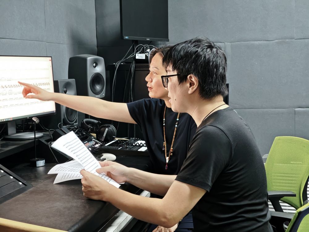 团队主创成员王欣、王子堃(前)在讨论修改乐谱。(受访者供图)