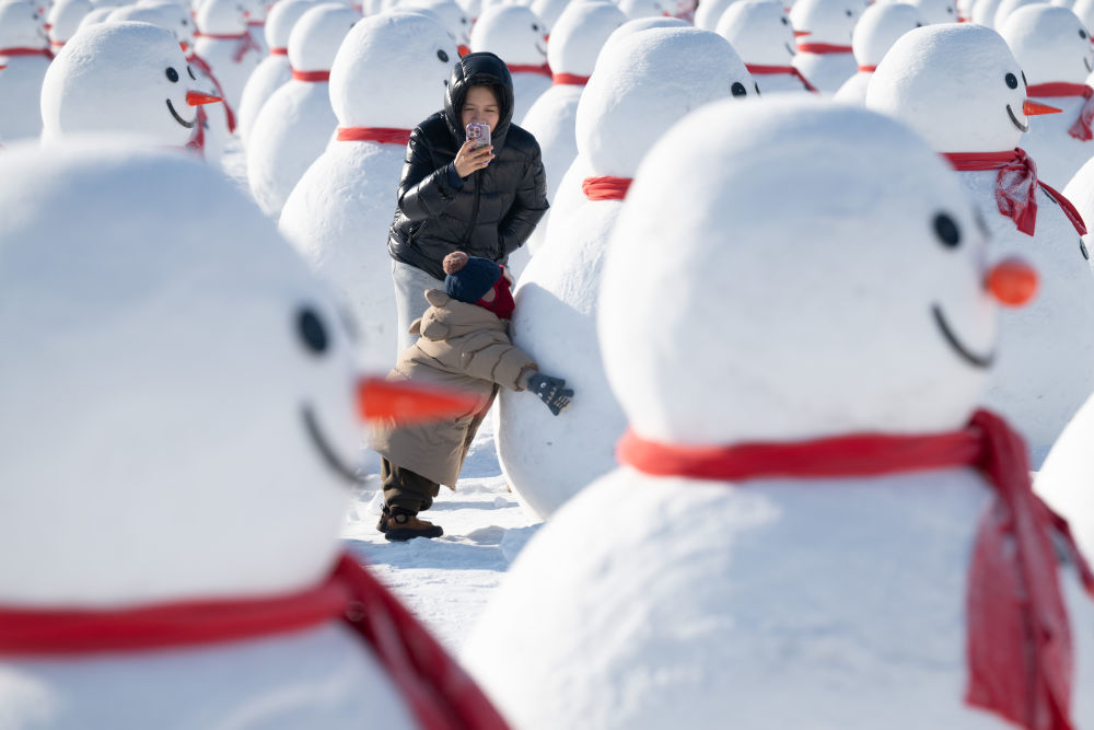 ↑1月4日，在北大荒集团闫家岗农场，游客与雪人拍照。新华社记者 张涛 摄