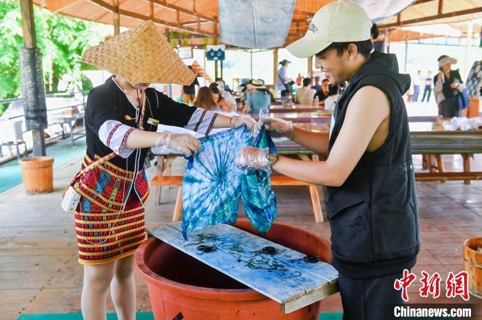 6月9日，印尼博主陈浩杰(右一)在海南槟榔谷黎苗文化旅游区体验苗族扎染。(海南省国际文化交流中心 供图)