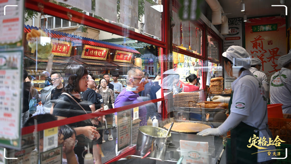 市民游客在天津市红桥区西北角特色街区购买煎饼果子。