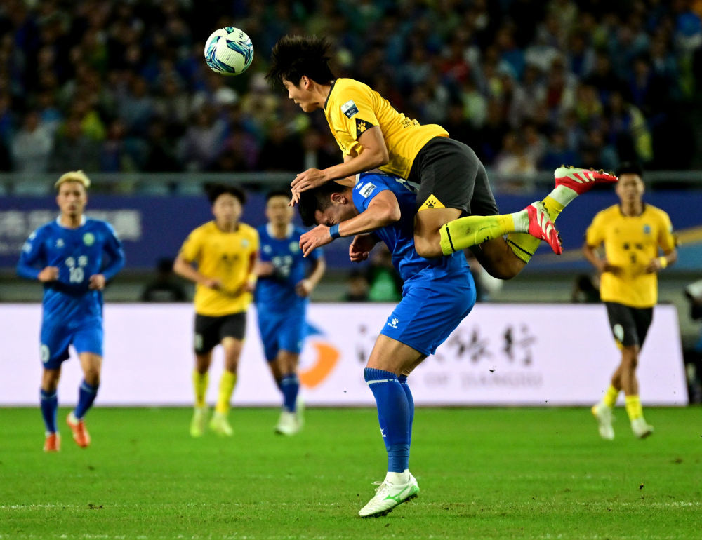 2025年10月18日,在“苏超”半决赛中,泰州队球员(上)与南京队球员争顶头球。新华社发(曹政 摄)