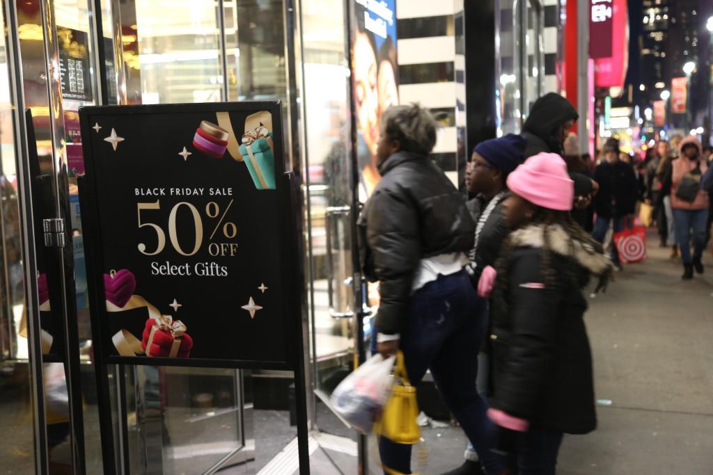 2024年11月29日,在美国纽约曼哈顿岛的一家商场外,人们经过“黑色星期五”促销广告牌。新华社记者刘亚南摄