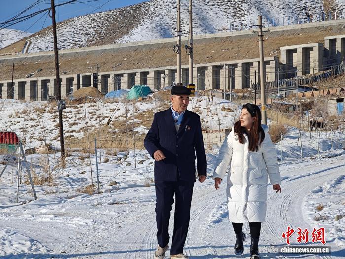 图为家住萨尔达坂乡哈那提·努尔哈孜(图左)向村里的年轻人介绍牧民转场的变化,背后就是12月26日通车的乌尉高速公路。 苟继鹏 摄