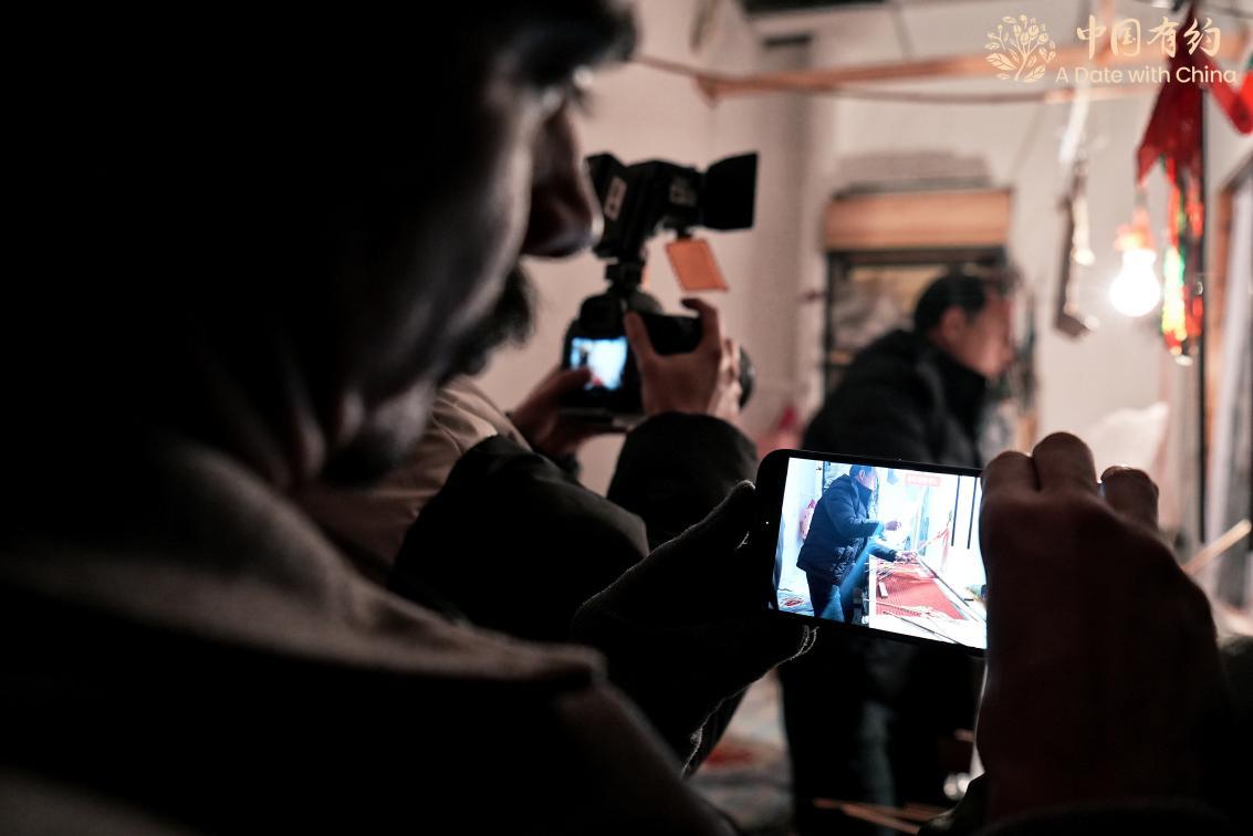 外国朋友用相机记录皮影戏表演。
