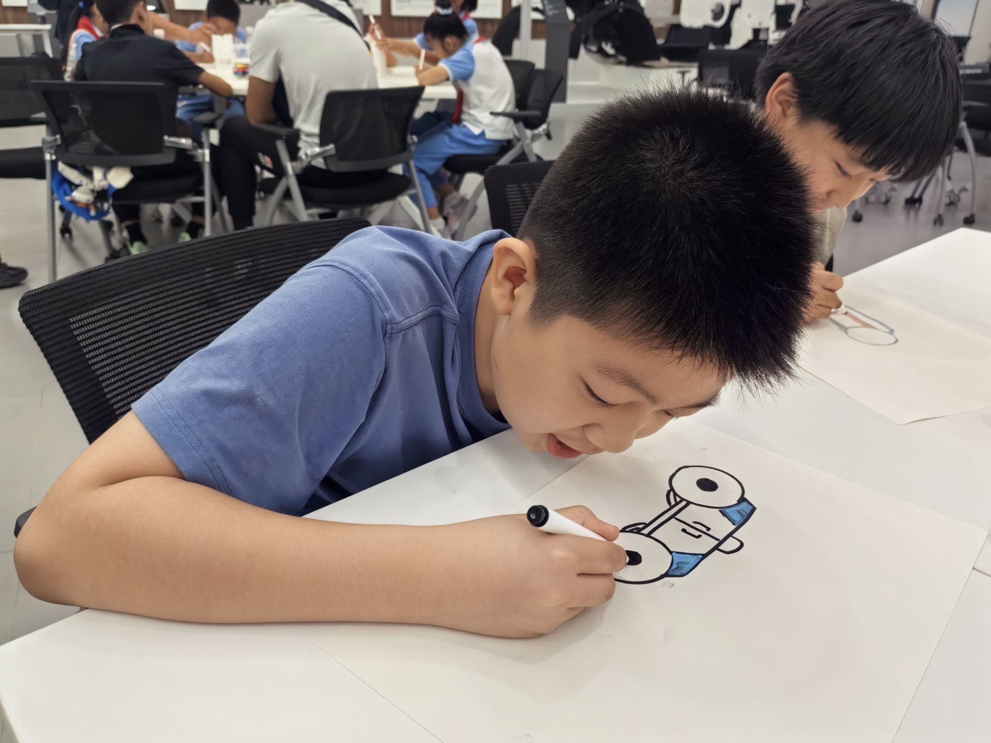 在创意分享会上，小朋友正在描绘未来的汽车是什么样的。