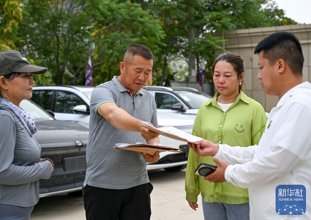 在新疆霍尔果斯一家汽车贸易公司,公司负责人(左二)向“摆渡人”发放车钥匙和出关所需资料(6月10日摄)。