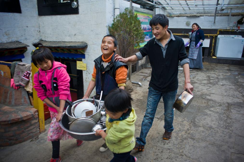 2013年10月12日，达瓦次仁（左二）跟同学们将洗好的餐具抬回厨房。