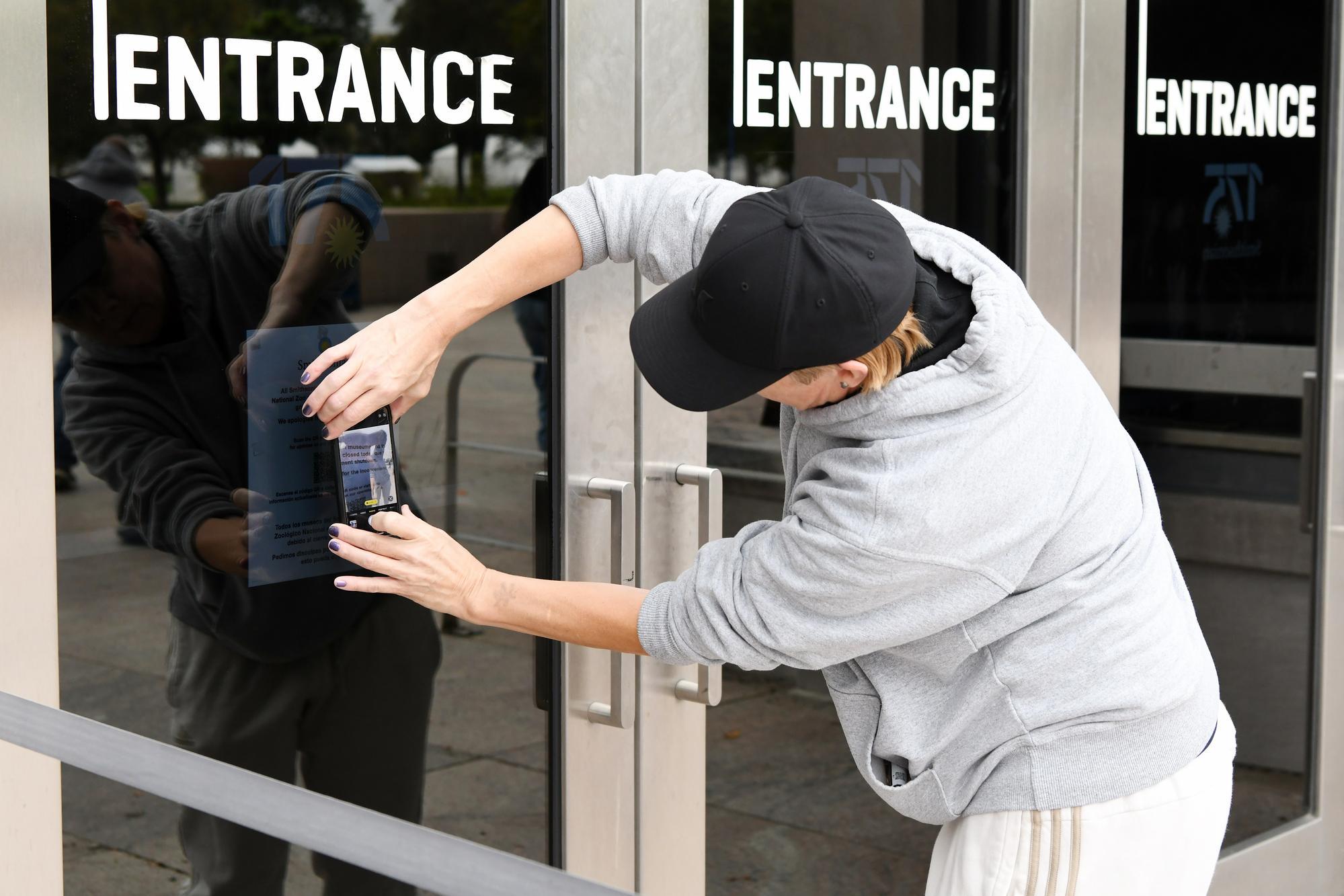 10月12日,在美國華盛頓,一名女子拍攝美國國家歷史博物館因聯邦政府“停擺”而關閉的公告。新華社記者李睿攝