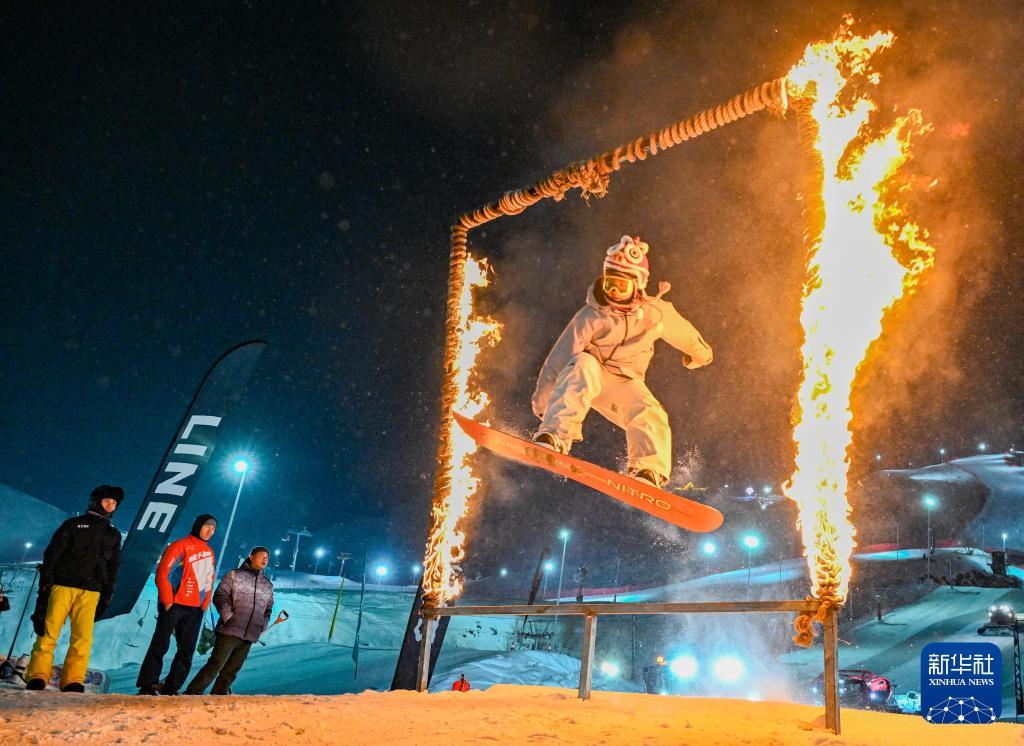 2025年1月29日，在坐落于阿勒泰市城区的新疆将军山国际滑雪度假区，雪友在新春趣味滑雪公园跳台活动中钻过火圈。新华社记者陈朔摄