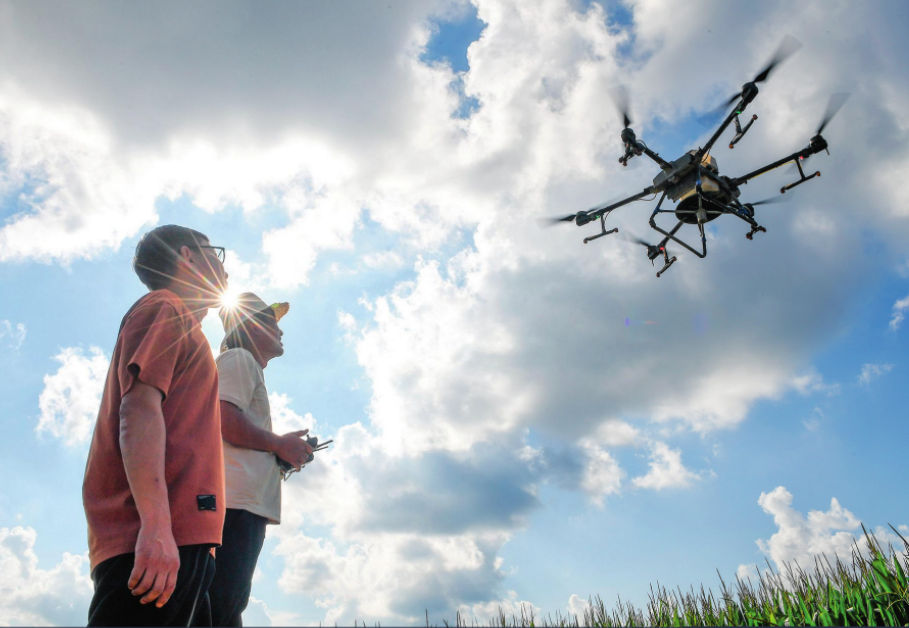 在吉林省梨树县孤家子镇,孤家子镇农业发展服务站高级农艺师兰雨壮(左)和无人机操作手一起查看植保无人机作业情况(2024 年 8 月 8 日摄) 张楠摄 / 本刊