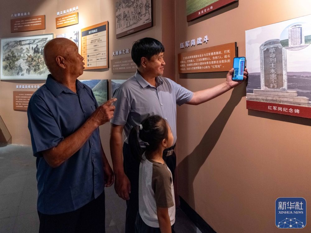 ↑8月23日,内蒙古呼伦贝尔市阿荣旗,孙福贵(右)在呼伦贝尔东北抗联纪念馆中向家人展示由他粉刷的老纪念碑。新华社记者 马金瑞 摄