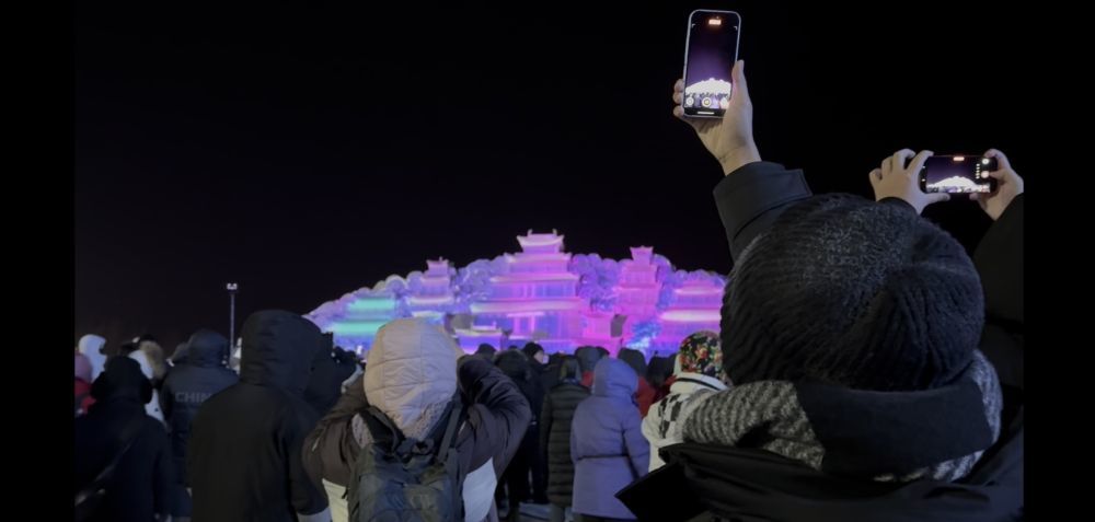 12月26日,第七届长白山粉雪节开幕,游客们在“云顶天宫”雪雕前打卡拍照。新华社记者金津秀 摄