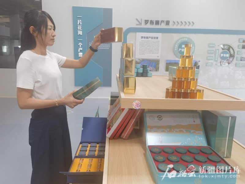 7月16日，在尉犁县罗布麻茶蜜有限公司的展厅里，工作人员整理罗布麻茶蜜产品。汪志鹏摄