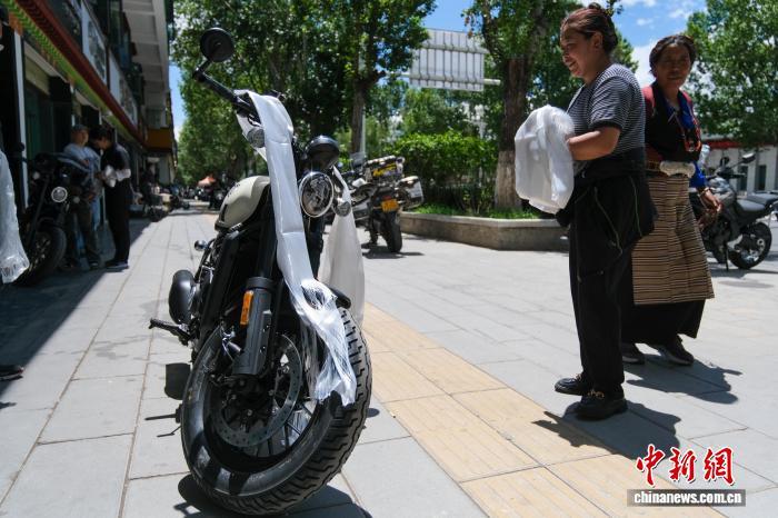 7月21日，拉萨一摩托车销售店销售员德吉(右二)为一台刚卖出去的摩托车披上哈达，并祝福车主平安骑行。 中新社记者 江飞波 摄