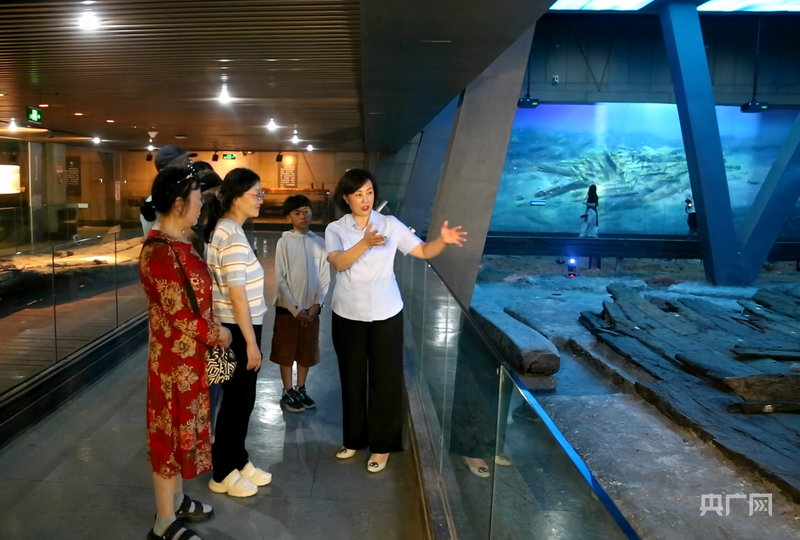 刘莉正在给游客讲解古船的来历(央广网记者 唐磊 摄)