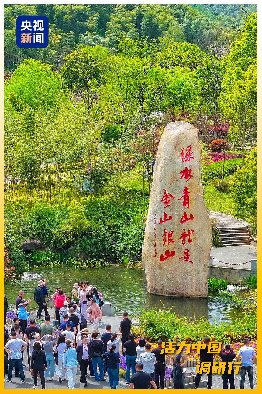 △游客在余村“两山论”石碑下拍照留念