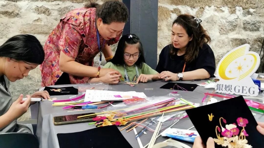 (唐彩萍在澳门教小朋友制作麦秆画)