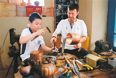库车市第七代铜器制作技艺传承人买买提&middot;卡地（右）在工作室向徒弟传授古老的铜器制作技艺。