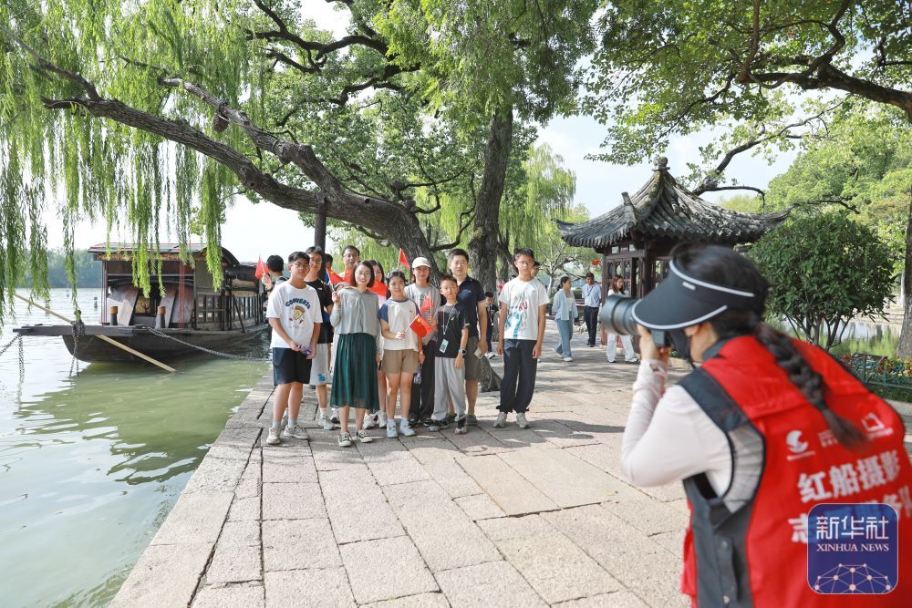 ↑ 10月1日,在浙江省嘉兴市南湖景区湖心岛,游客与“红船”合影。新华社发(金鹏摄)
