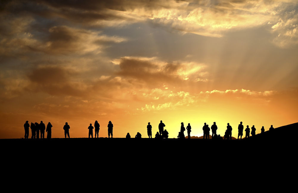 这是10月2日清晨,游客在甘肃省敦煌市鸣沙山月牙泉景区观赏大漠日出美景。新华社发(张晓亮 摄)