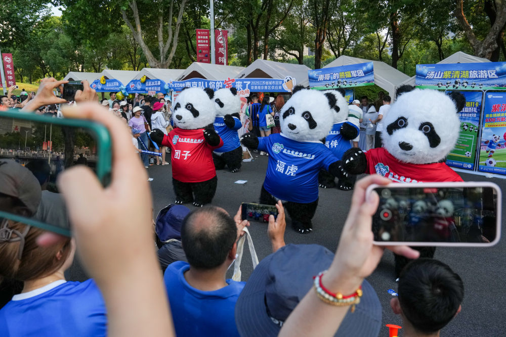 7月5日,在江苏南京举行的2025江苏省城市足球联赛第六轮比赛前,球迷在场外的文化市集观看表演。新华社记者 李博 摄