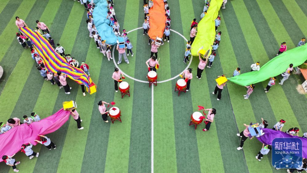 ↑ 5月23日，在山东省东营市广饶县李鹊镇中心幼儿园，小朋友在进行龙舟赛游戏（无人机照片）。新华社发（刘云杰摄）
