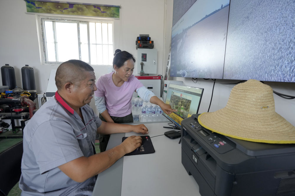 在山西省运城市盐湖区解州镇曲村,董会龙(左)和妻子范月亲通过农机精准作业平台查看农机手作业情况。董会龙夫妻是运城市盐湖区解州镇的种粮大户。(5月27日摄)。