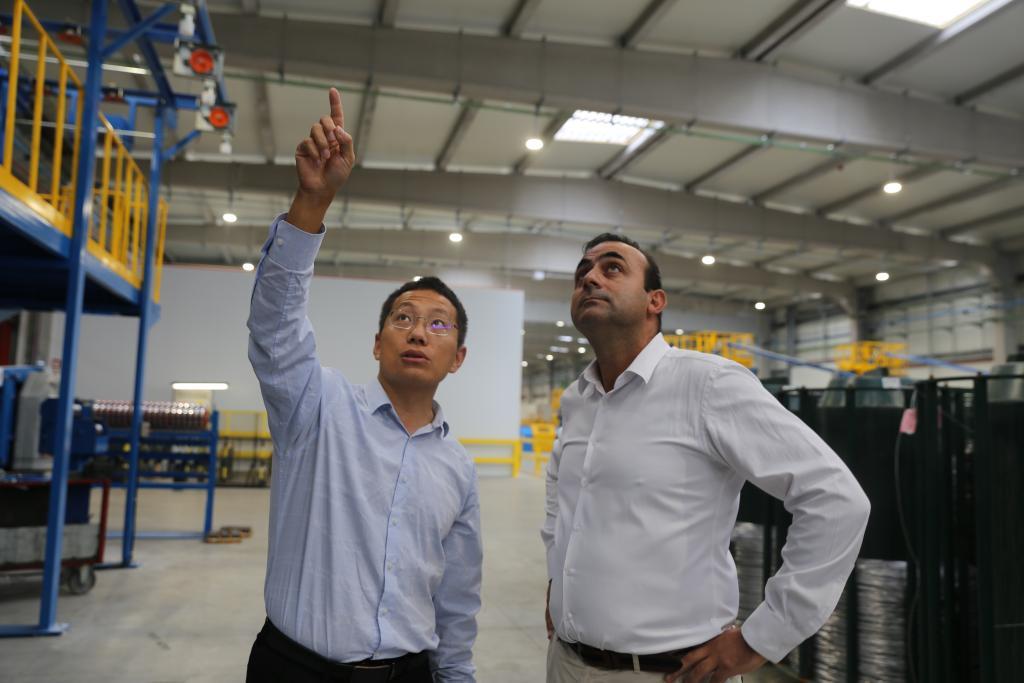 10月3日,在葡萄牙北部奥瓦尔市,亨通集团驻葡萄牙的设备经理刘建龙(左)与阿尔科夫雷电缆厂首席运营官卡洛斯·格兰雅讨论技术问题。新华社记者荀伟摄