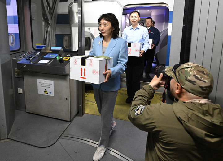 护送文物归国的工作人员手捧装载着子弹库帛书的保护箱走出客机（2025年5月18日摄）。新华社记者 李贺 摄