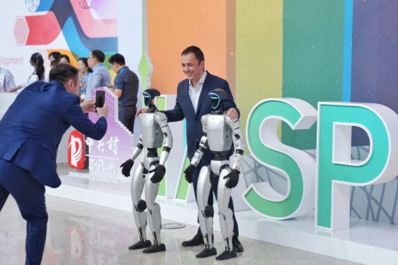 2025年9月17日，国际科技园及创新区域协会(IASP)2025年世界大会在北京国家会议中心开幕。图为外籍嘉宾在大会现场同机器人合影。中新社记者 张祥毅 摄