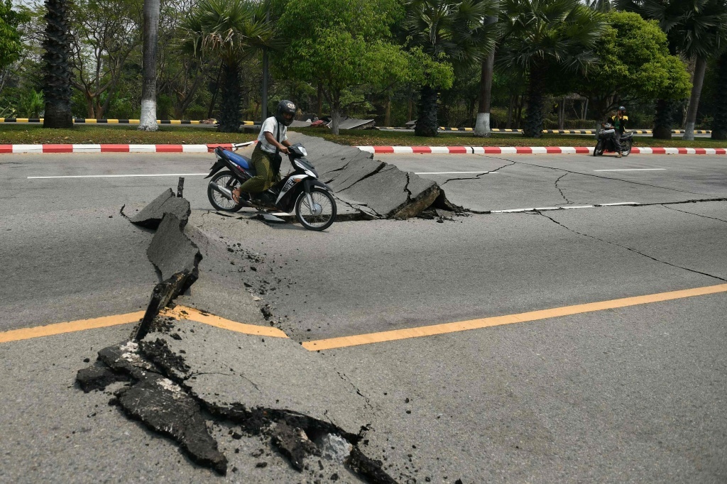 当地时间2025年3月28日,缅甸内比都,一名摩托车骑士驶过一条遭到损毁的道路。