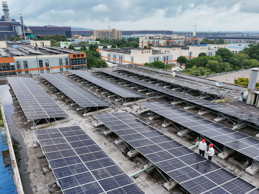 9月17日，在四川都江堰经济开发区，朱鹏宇（左）和同事检查工业用户新装屋顶光伏板情况（无人机照片）。新华社记者 王曦 摄