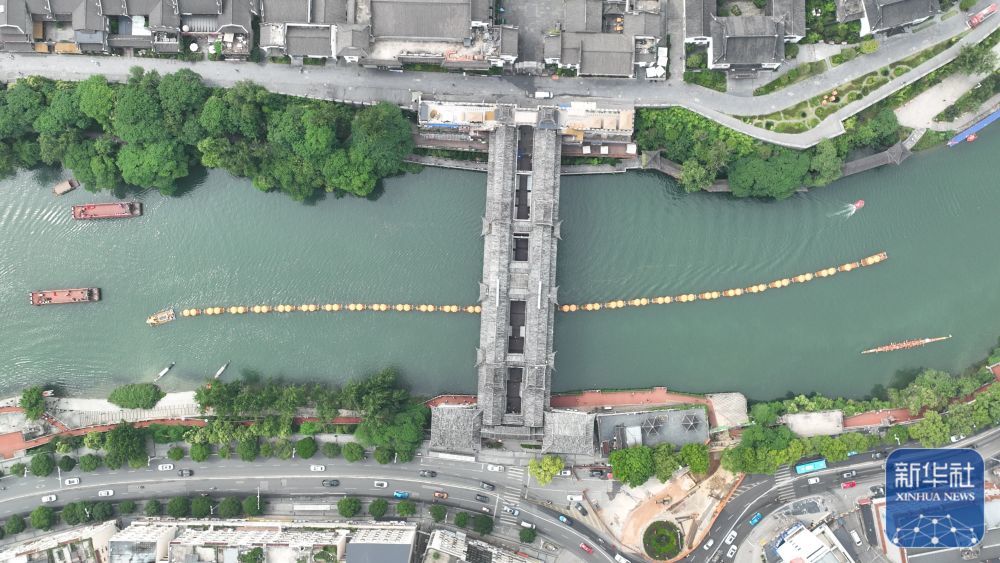 ↑ 5月24日，在贵州省铜仁市碧江区锦江水域，观光龙舟从风雨桥下穿过（无人机照片）。新华社发（申逸恺摄）