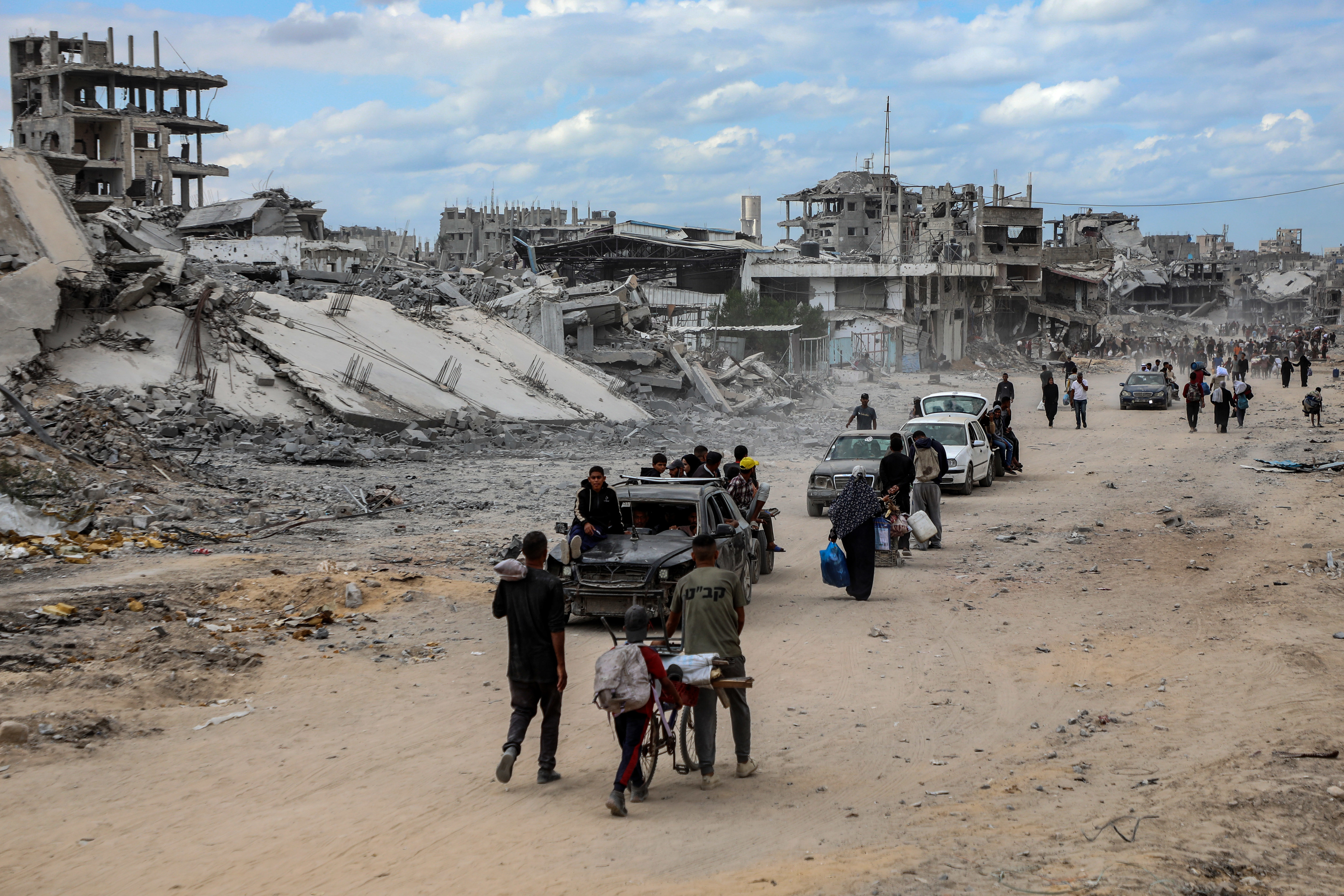 10月12日,在加沙地带南部汗尤尼斯,重返家园的巴勒斯坦人走过严重受损的建筑。新华社发(里泽克·阿卜杜勒贾瓦德摄)