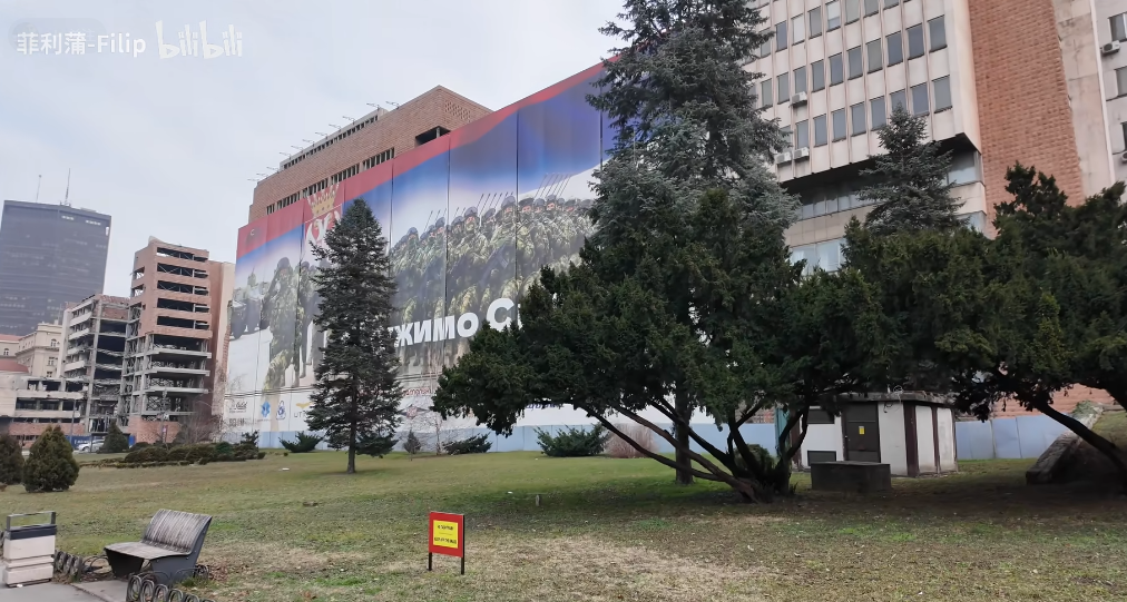 一块类似征兵广告的广告牌遮挡了被炸的大楼;据说美国希望塞尔维亚为了“美塞友好”考虑,遮一遮残骸。