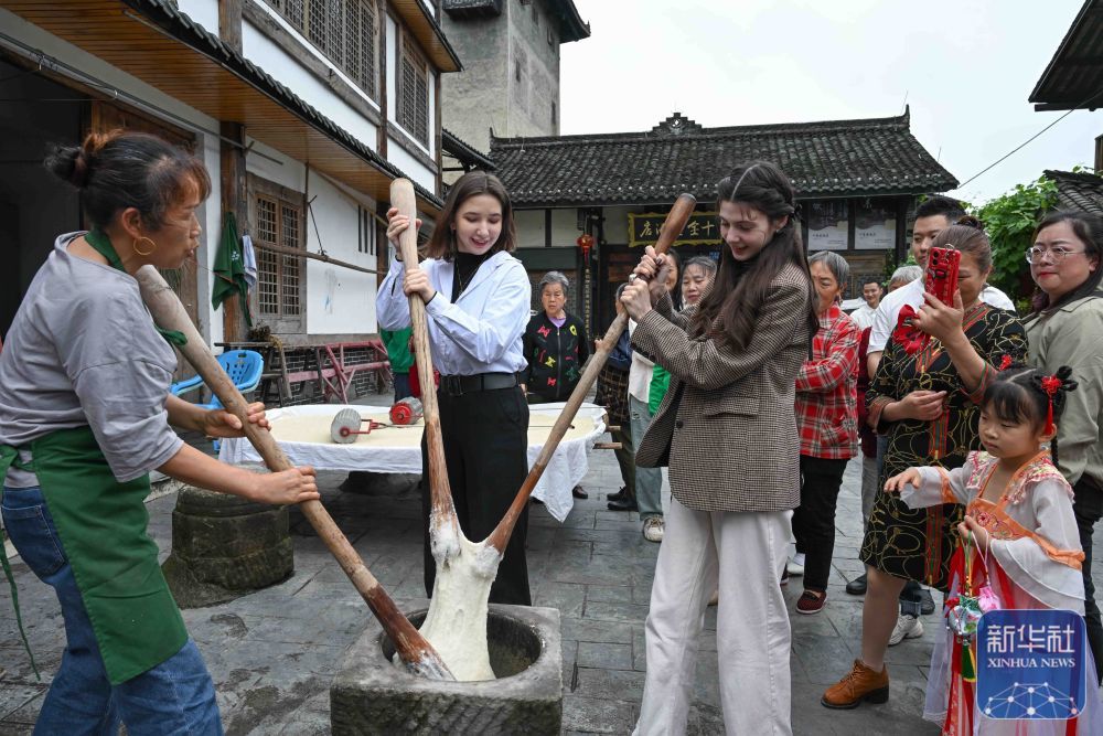 5月28日，在重庆市巴南区丰盛古镇，就读于重庆大学的俄罗斯留学生奥莉（前中）、哈萨克斯坦留学生玛丽（前右二）与居民一同体验打糍粑。