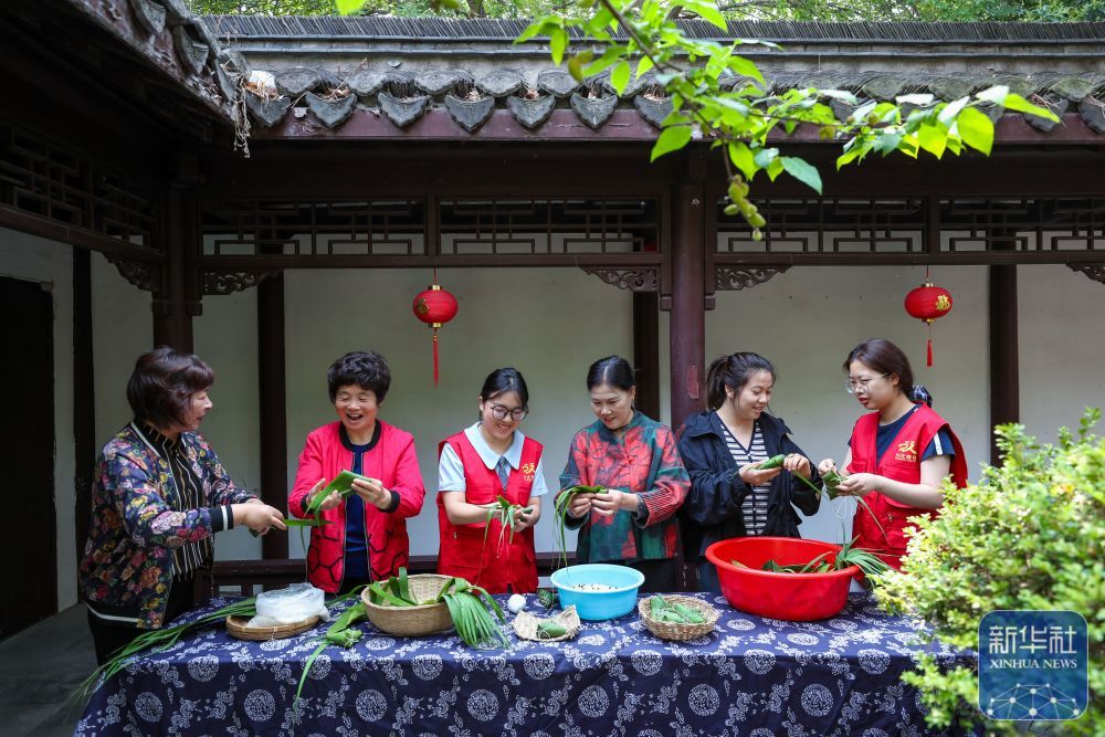 ↑ 5月24日，在位于江苏省兴化市昭阳街道的兴化书院，青年志愿者和社区居民一起包粽子。新华社发（周社根摄）