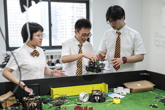 郑思诚、刘郡洁和葛子砚在研究他们通过3D打印制作的足球机器人