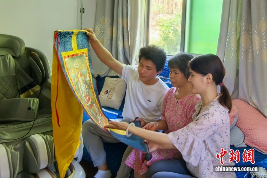 图为黄小芳(右一)为家人介绍唐卡。 受访者供图