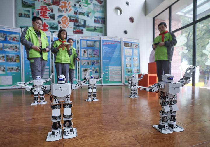 在浙江嘉兴市实验小学科技城校区科创中心内，智能机器人社团的学生们对编码完成的智能机器人进行动作指令调试，并使用平板统一控制多台智能机器人完成舞蹈表演（2025年3月12日摄）。新华社记者 徐昱 摄