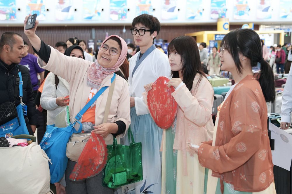5月1日，游客在天津国际邮轮母港客运大厅与演出人员合影。