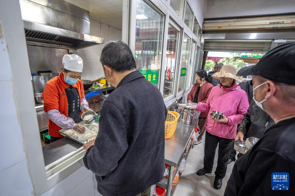 在昆明市幸福家园小区爱心食堂,王兰兰(左一)给老人打饭(5月28日摄)。