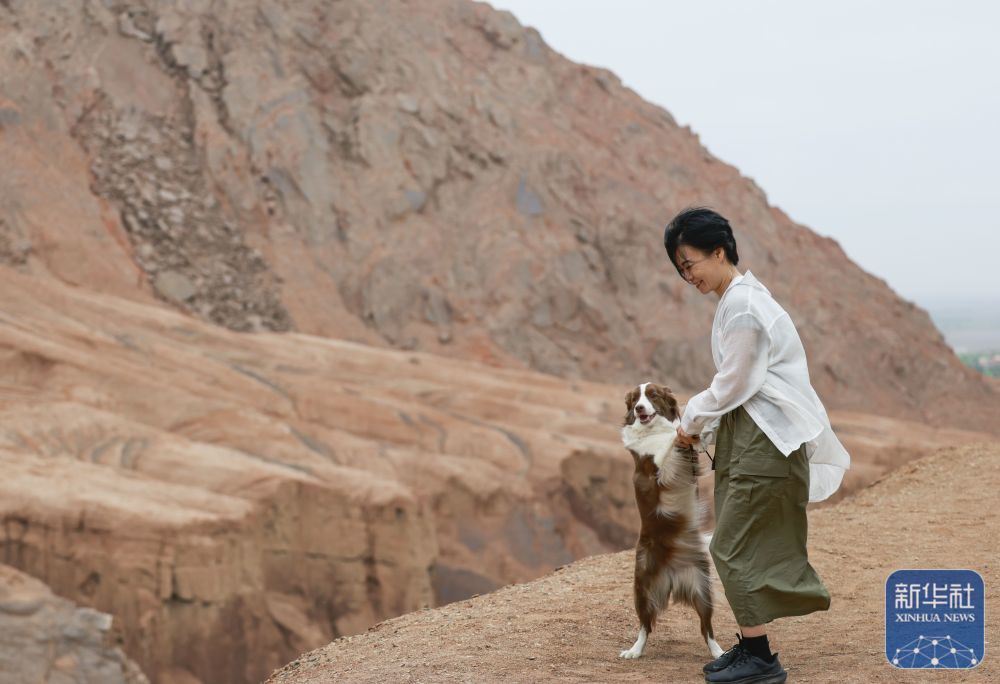 ↑ 5月4日,一名携带宠物的游客在位于新疆吐鲁番市鄯善县的吐峪沟大峡谷游玩。
