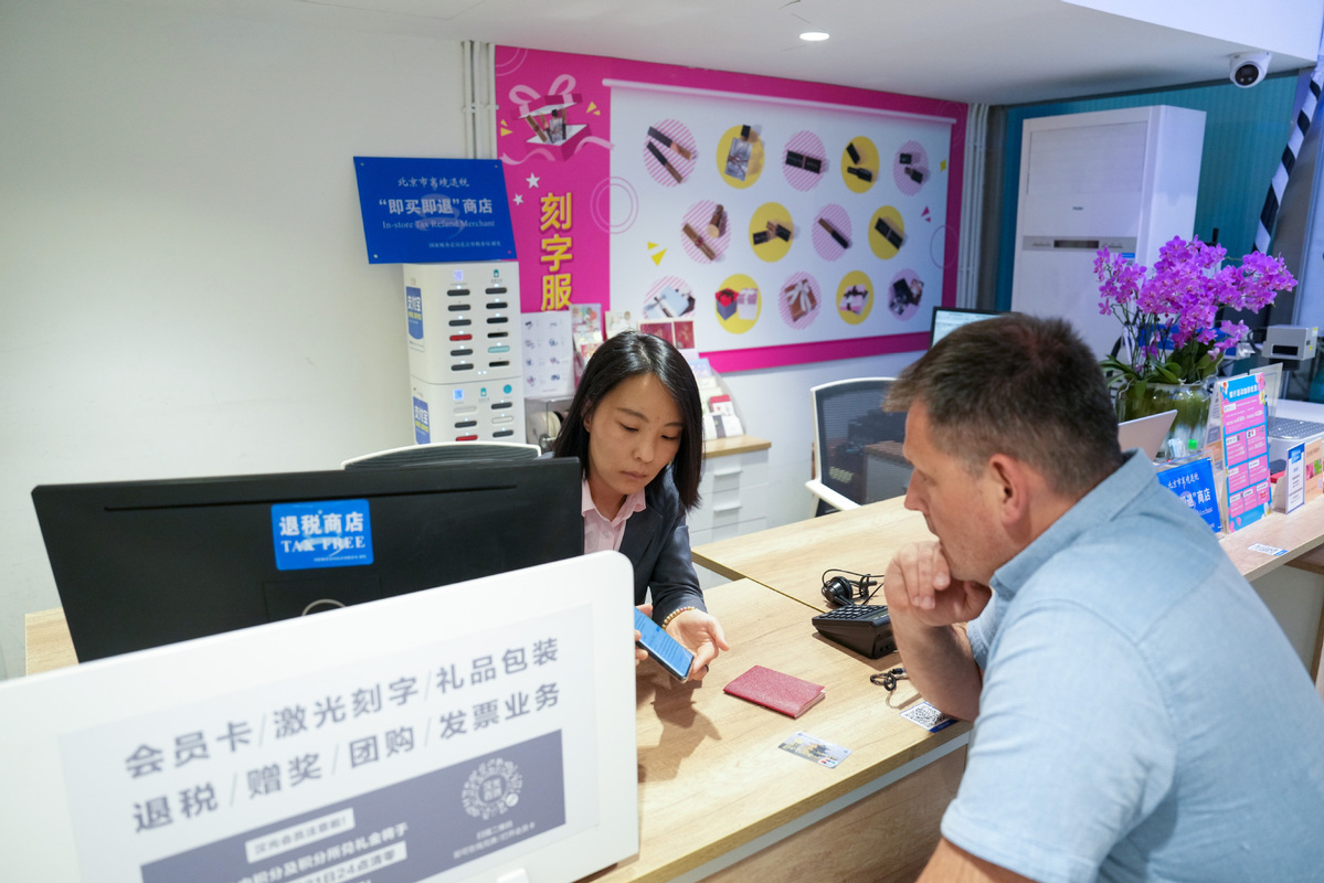 4月30日，在北京汉光百货内的退税柜台，工作人员（左）为一名俄罗斯顾客办理离境退税“即买即退”业务。（图片来源：新华社）