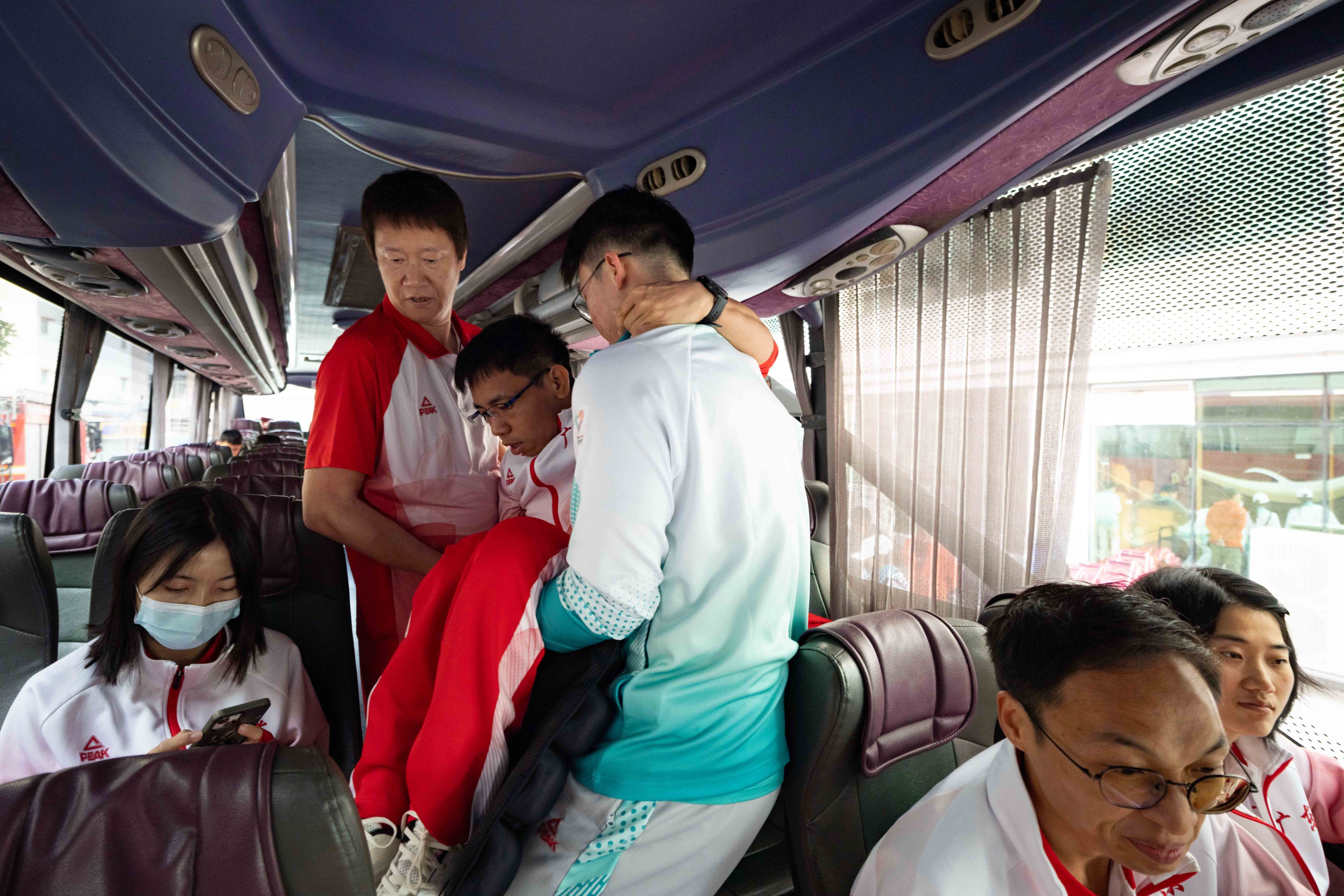 出发前，助教张健忠将行动不便的队员们逐一抱上大巴。