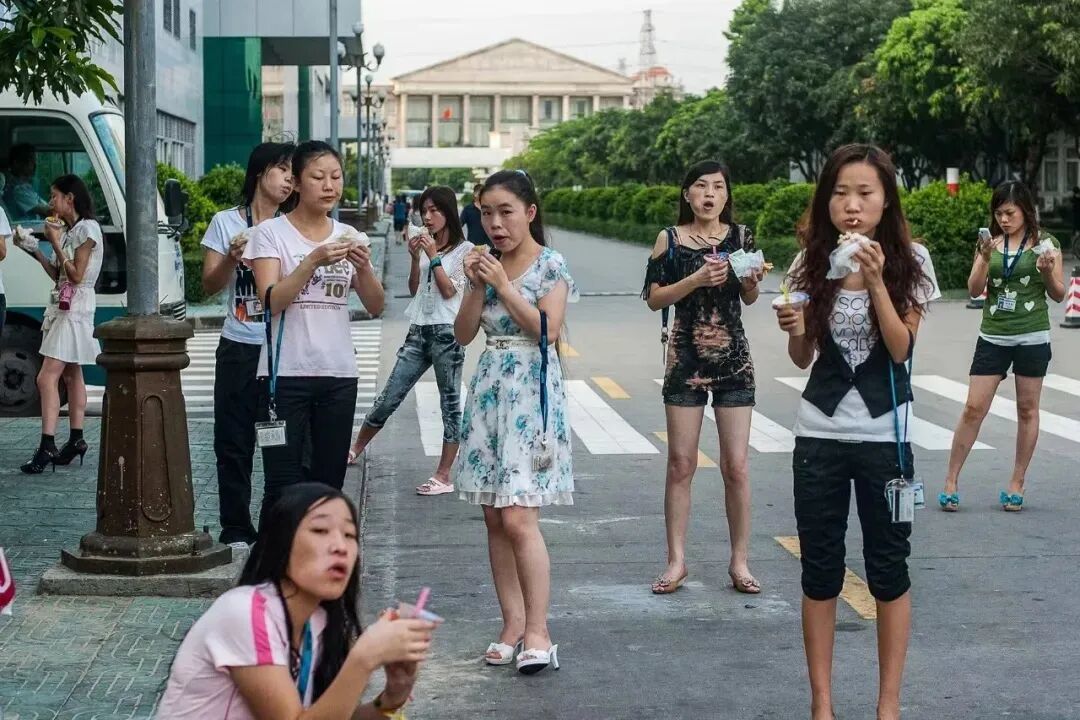 早上上班前,电子厂的女工,买好早餐后站在路边上吃,然后上班。