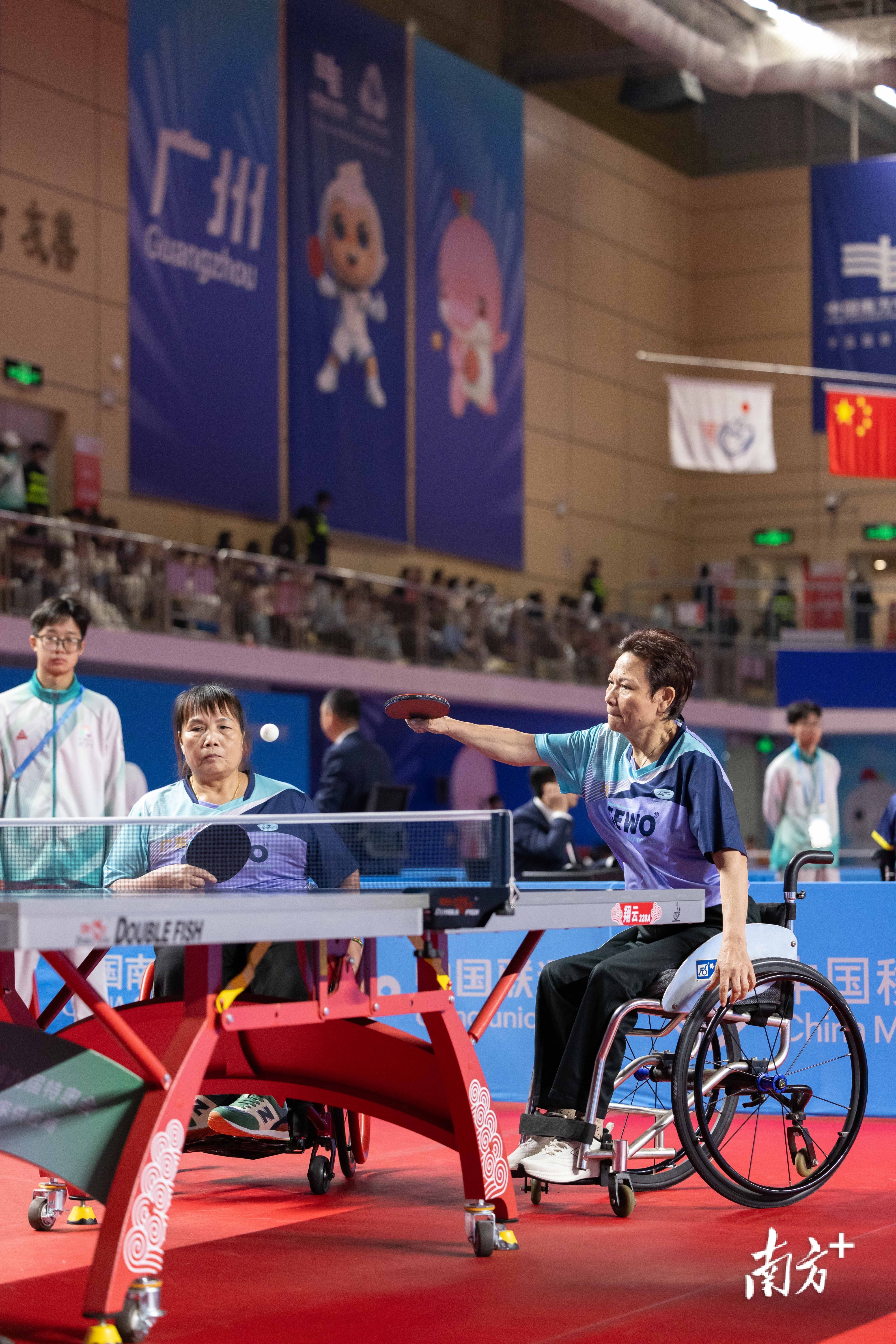 12月8日,在兵乓球TT5女子双打小组赛中,黄丽明(右)撑起身子击球。