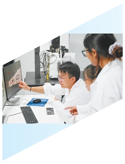 黄宇轩（右三）等团队成员正在试验平台查看楔形劈刀的显微照片，讨论技术方案。　　本报记者 孙 超摄