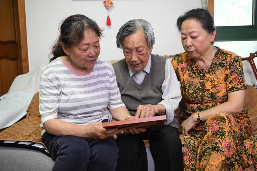 ↑2025年5月21日，夏淑琴（中）在南京家中和女儿张雪萍（左）、张学霞一起看老照片。